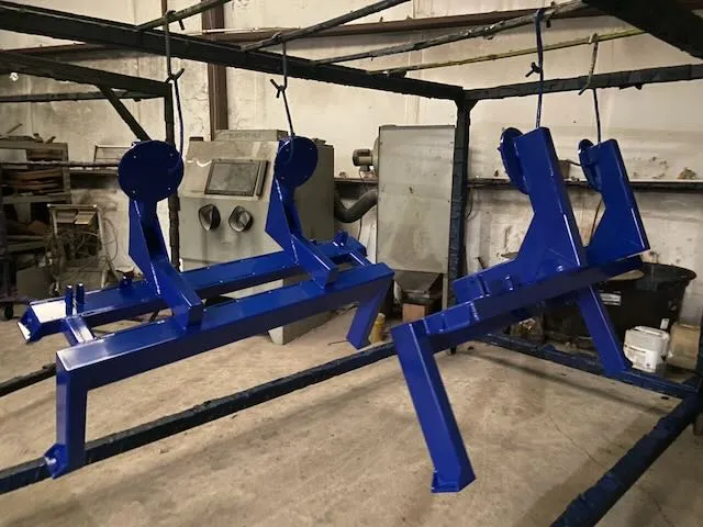 Two blue powder coated frame assemblies hanging in coating booth